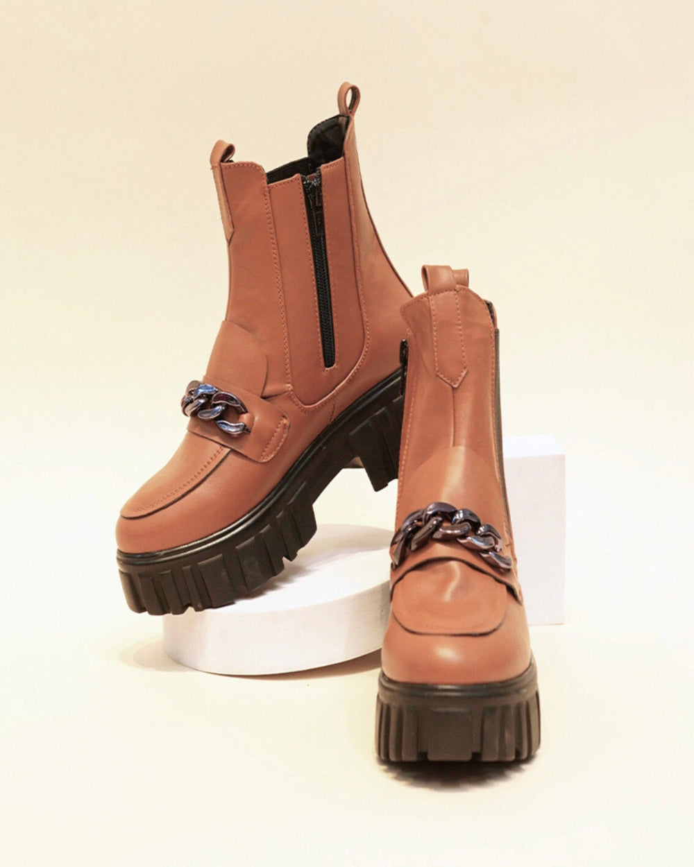 Tan handcrafted side zipper ankle boots with chunky black soles and decorative front chain detail