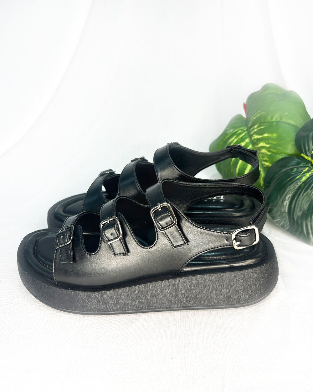 Black triple buckle sandals with cushioned footbed and adjustable straps in vegan leather
