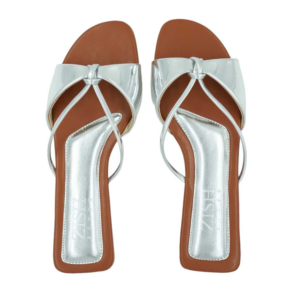 Pair of Silver Carolina Flats with glossy mirror straps and brown footbeds, vegan leather open-toe sandals.