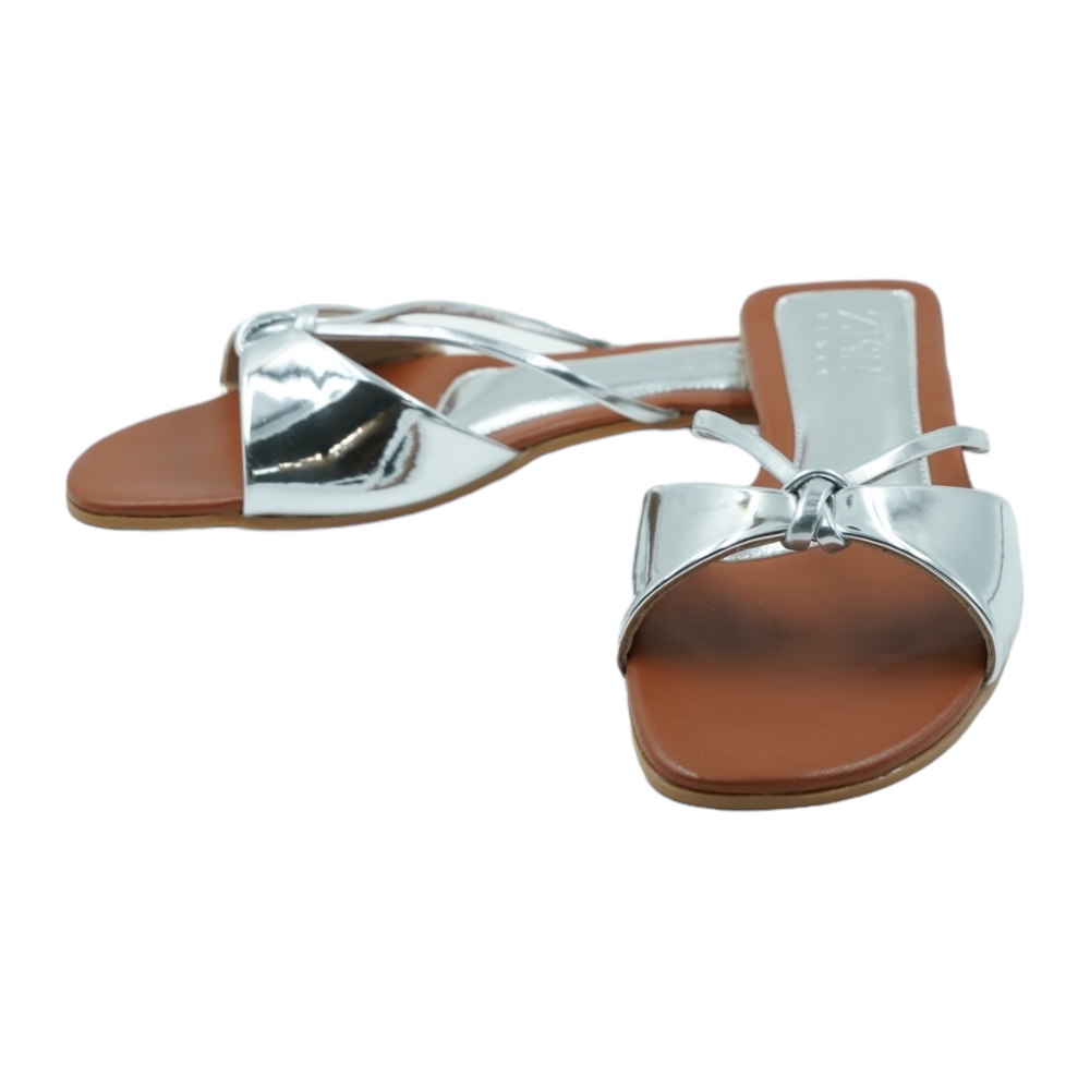 Silver Carolina Flats with glossy mirror strap and brown footbed, open-toe vegan leather sandals for casual and formal wear.