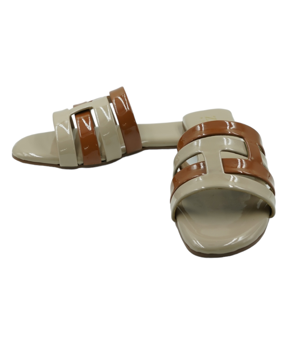 Beige Azzura Flats open-toe geometric design sandals in beige and tan vegan leather with flat PVC sole.