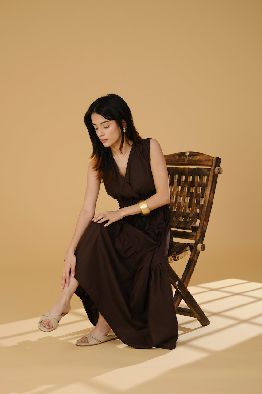 Woman wearing beige Tokyo flats with cross-strap design sitting on wooden chair against beige background