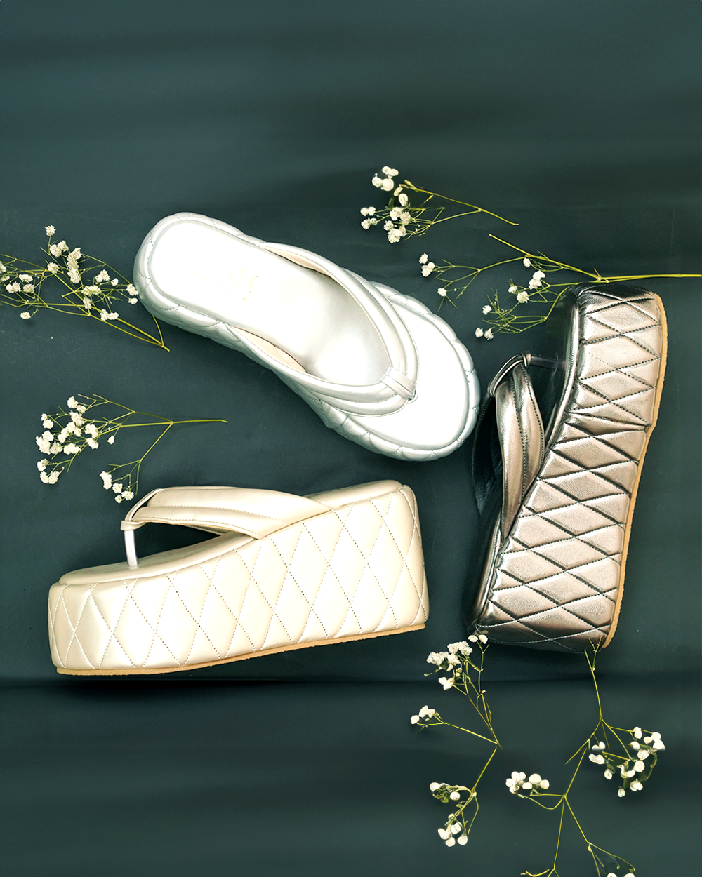 Silver Pinnacle Platforms chunky heel sandals with quilted design and open toe in silver and beige colors on dark background with decorative white flowers