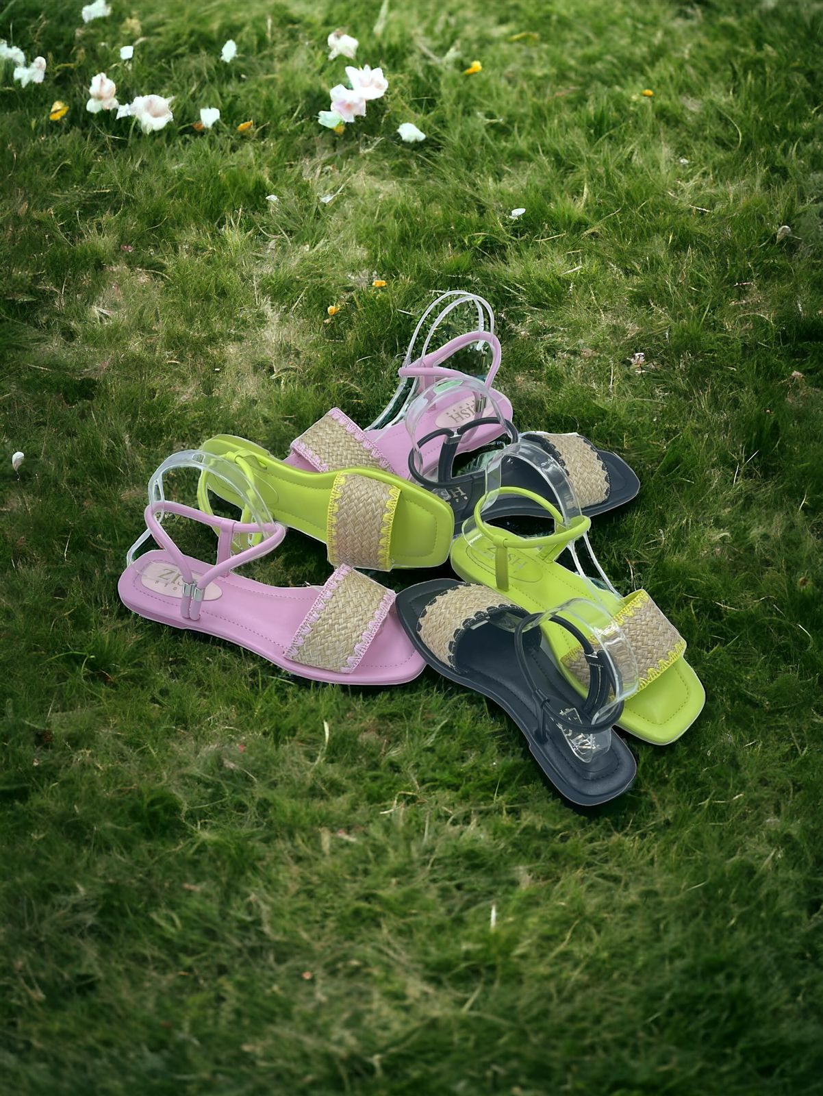 assorted colorful flat sandals with cane upper and open toe design displayed on grass surface