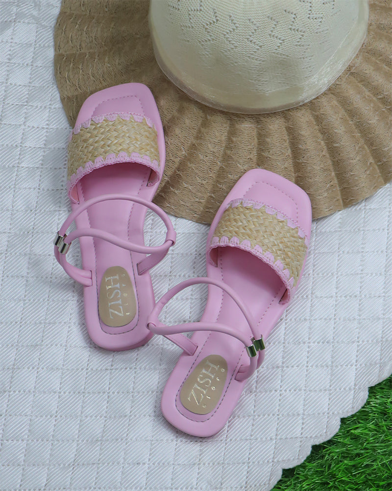 Pink Ocean Walker Sandals with cane upper and open toe flat design on a textured white surface next to a straw hat