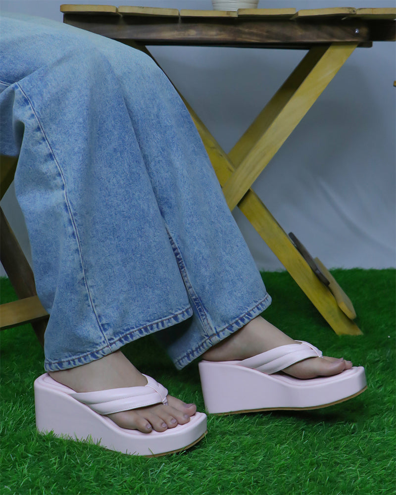 Pink platform wedge slides with simple strap in open toe design worn with blue denim jeans