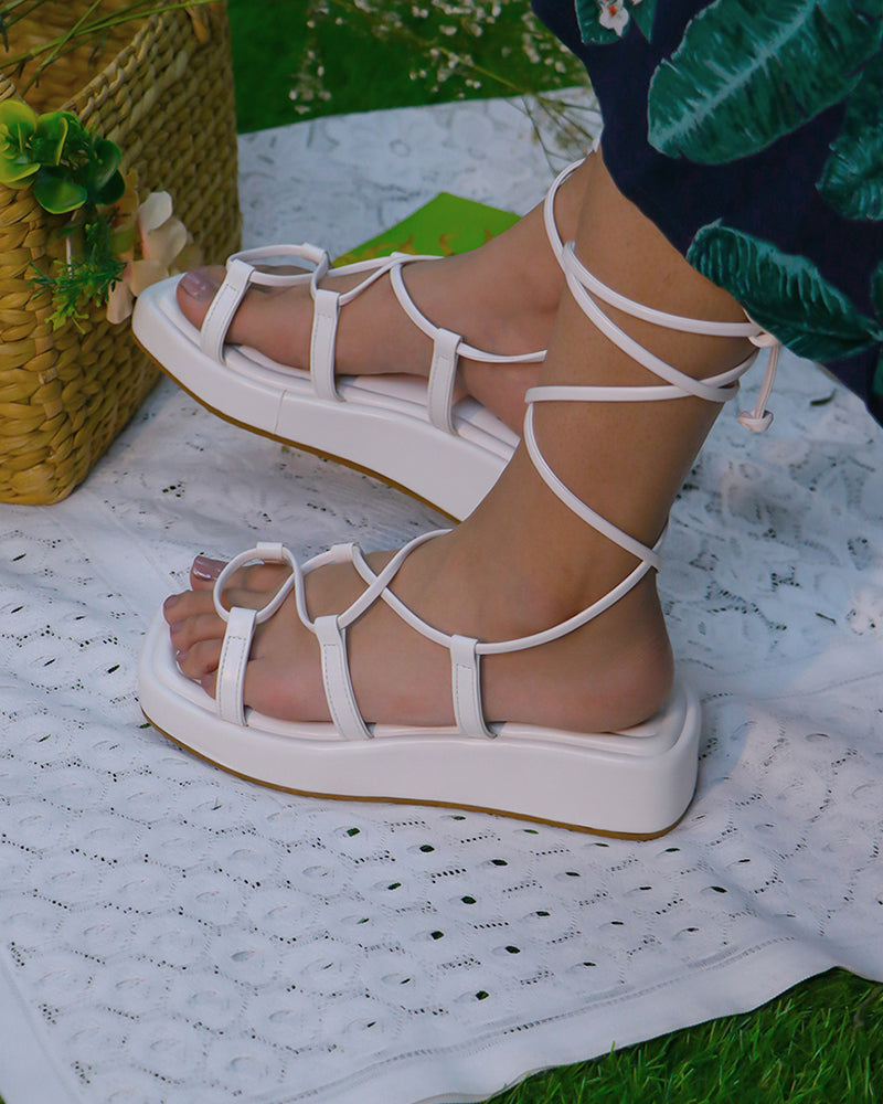 White platform tie ups flats with 1-inch sole and vegan leather straps on feet