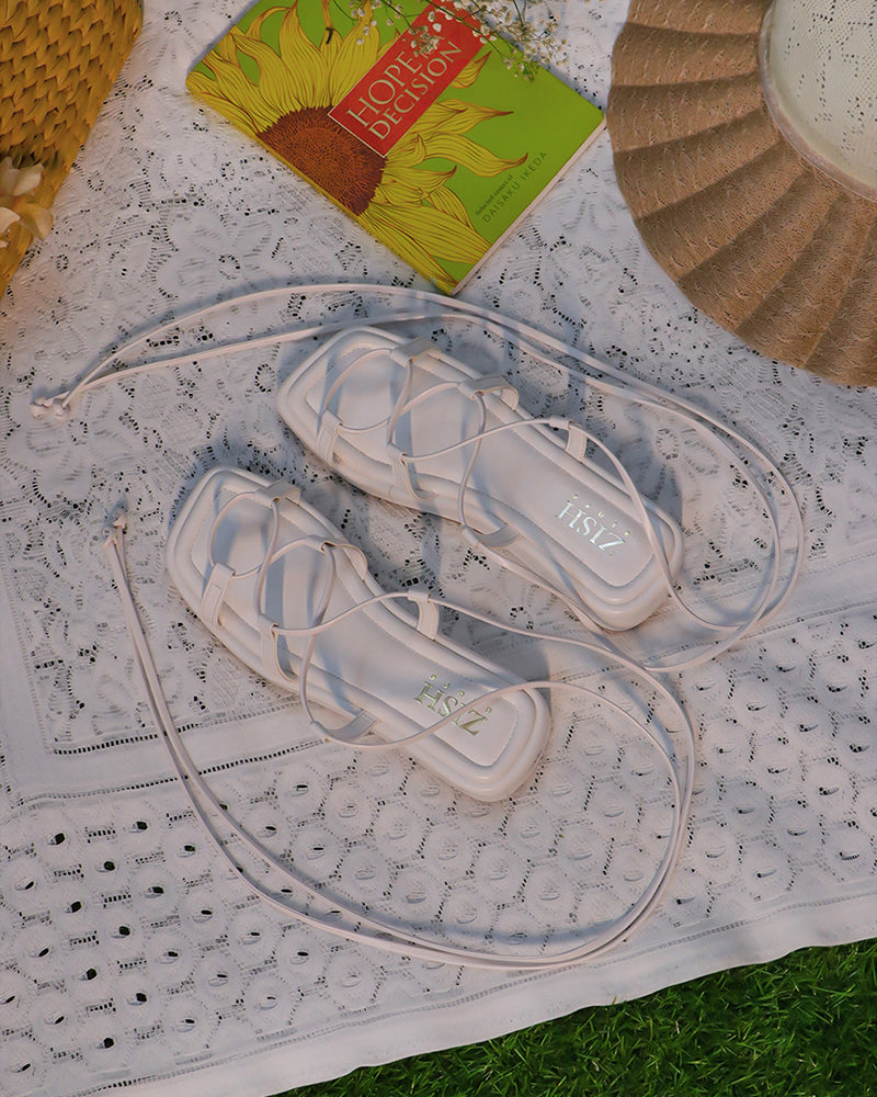 White platform tie ups flats with 1-inch sole and vegan leather material on lace cloth backdrop.