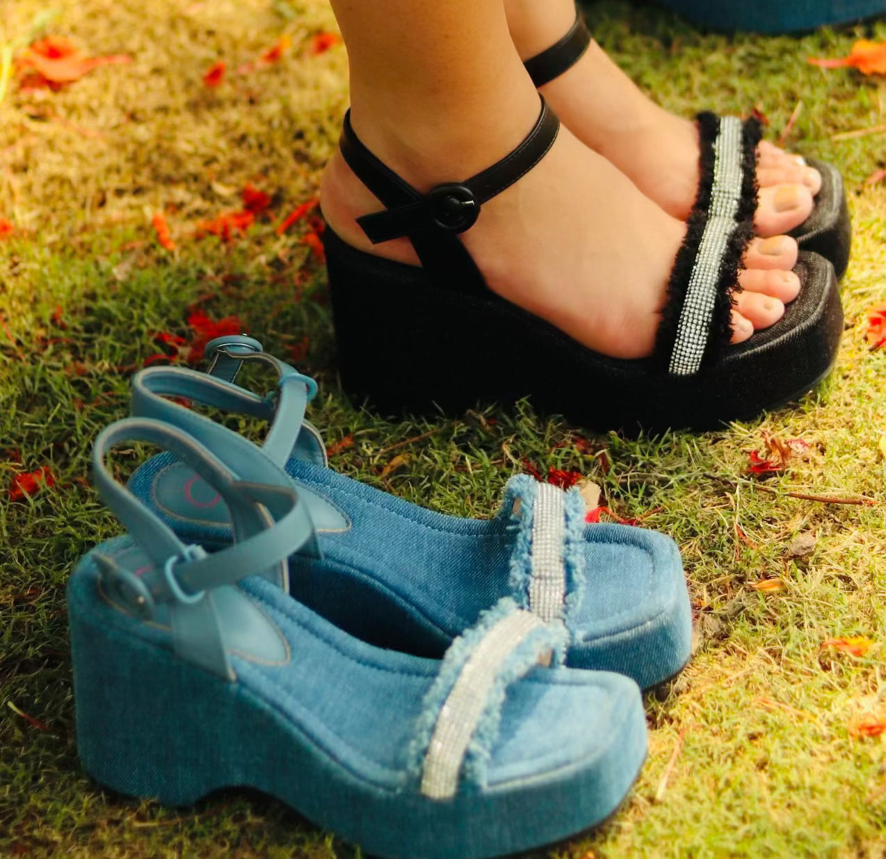 Black denim wedge sandals on grass with beaded strap detailing in black and blue colors